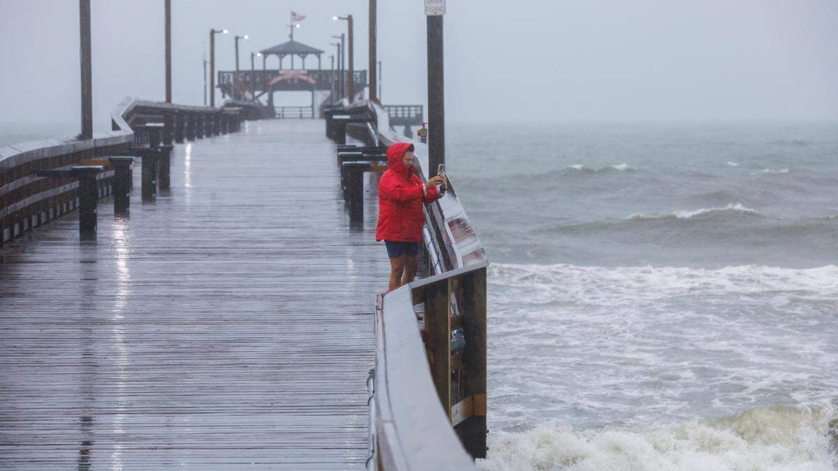 A woman takes pictures from Cherry Grove Pier at Prince Resort in North Myrtle Beach before Tropical Storm Debby in August 2024. Tropical Cyclone Eight is moving into the Myrtle Beach area around Sept. 16, 2024.