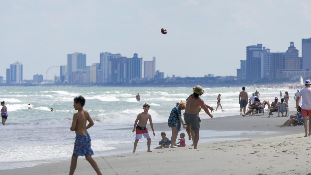 Looking North in the Shore Drive area of Horry County, tourists swim in the Atlantic Ocean as the Myrtle Beach skyline shows in the background. May 29, 2024.
