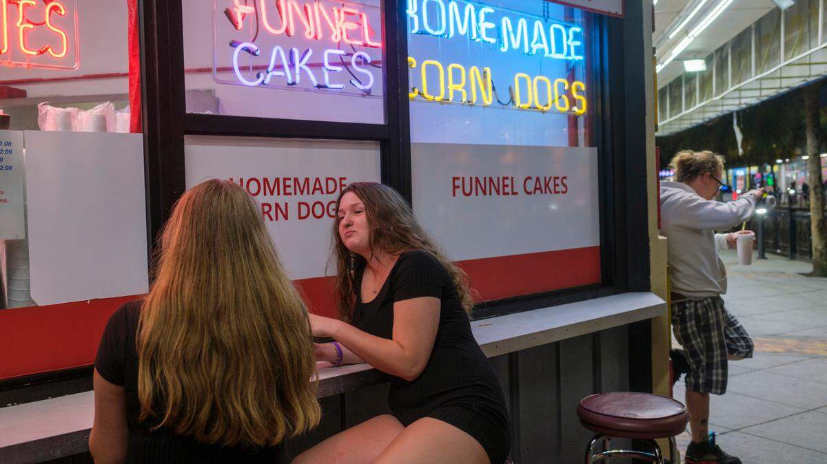 Emma Mullins and Kaitlyn Speaks of Statesville, NC took a break from ongoing negotiations with an air brush t-shirt seller to have a snack on Ocean Boulevard, Friday night. Downtown Myrtle Beach’s tourist district was relatively quiet for a Summer evening on Ocean Boulevard and the Boardwalk. Storms put a damper on the evening activities but as the skies cleared, visitors returned to enjoy the attractions. Friday, May 30, 2025.