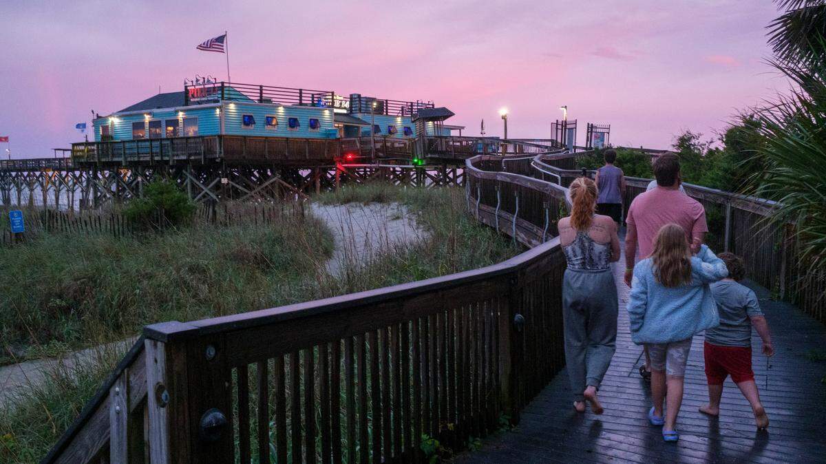 A family walks the Myrtle Beach Boardwalk to Pier 14 following a thunder storm Friday evening. Downtown Myrtle Beach’s tourist district was relatively quiet for a Summer evening on Ocean Boulevard and the Boardwalk. Storms put a damper on the evening activities but as the skies cleared, visitors returned to enjoy the attractions. Friday, May 30, 2025.
