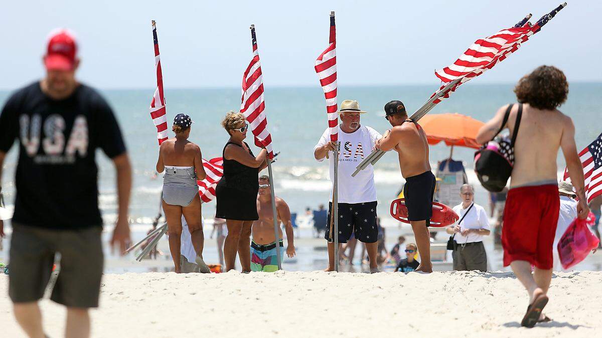 Flags are given to beachgoers to line the beach in the annual American Pride March in North Myrtle Beach on Monday, July 4, 2016. Volunteers started marching with flags from the north and south end of the beach around 11 a.m. and met on the beach at Main Street for a brief ceremony which coincided with the Salute From The Shore flyover.