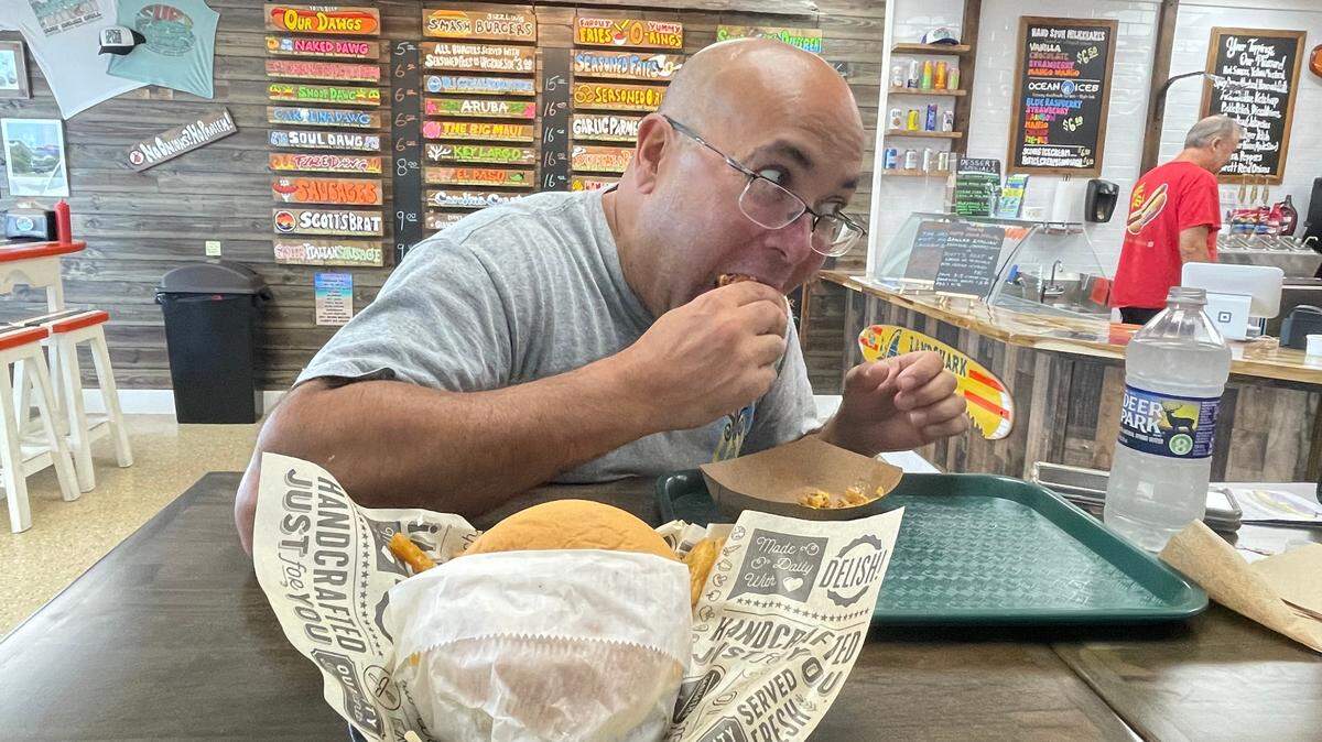 David McGaha, of Conway, tucks into a smash burger at Surf Dawgs in Surfside Beach on Aug. 22, 2024. McGaha has gained a following by posting his dining adventures on Facebook. He eats out every day, some times twice a day.
