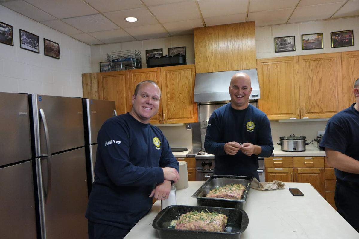 Firefighter Brendan D’Anna posing with the prime rib he was cooking to celebrate Christmas with his fellow firefighters at Station One.