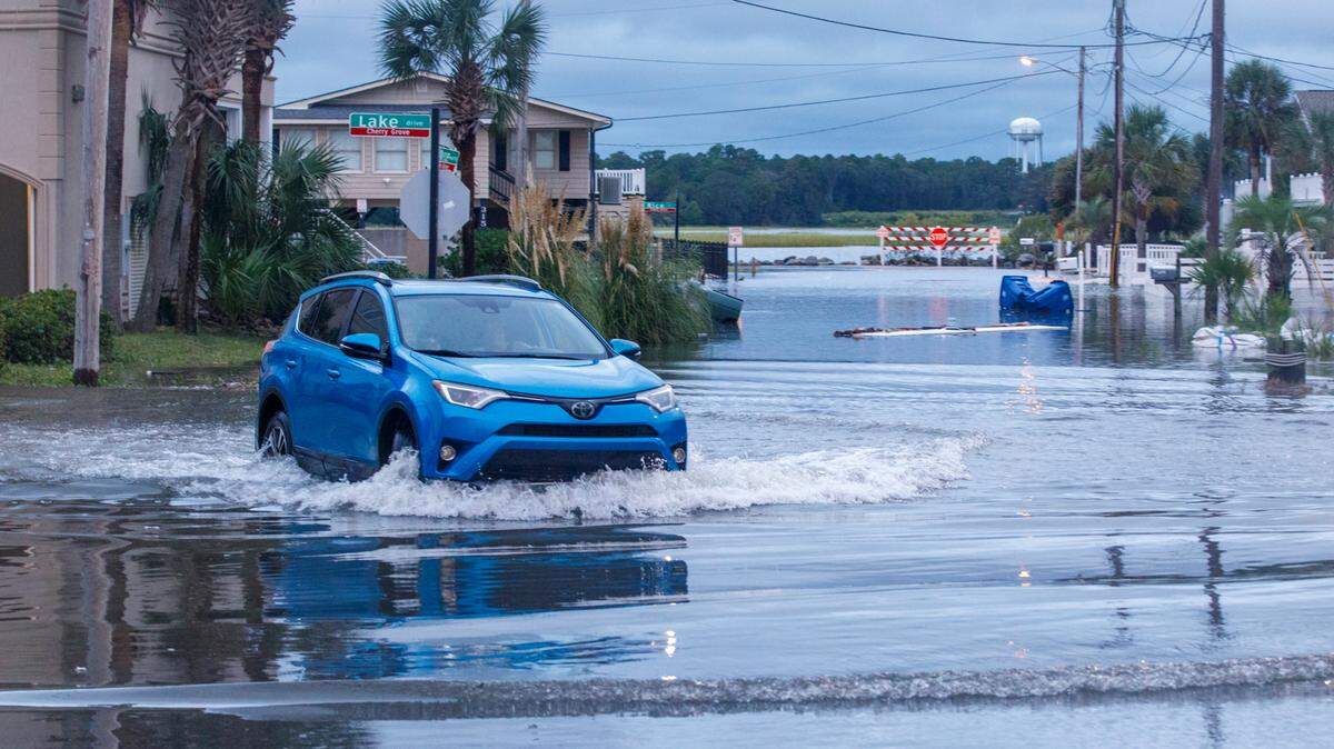 A car navigates through king tide flooding in Cherry Grove on Sept. 16, 2024. The 29582 ZIP code pays among the highest rates of flood insurance in the Grand Strand.