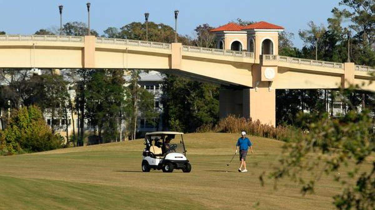Golfers get ready to hit their approach shot on the ninth hole, which plays along the Intracoastal Waterway, at the Grande Dunes Resort Course.