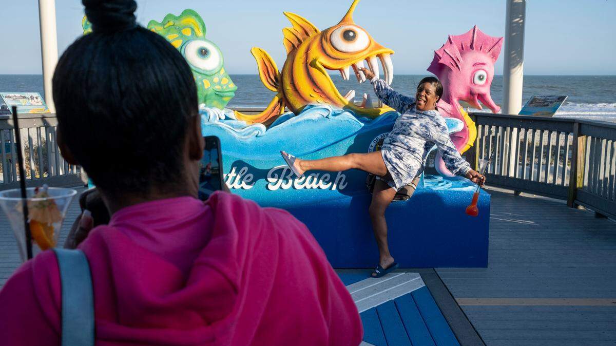 A Myrtle Beach tourist poses for a picture on the boardwalk on Friday. Grand strand residents and visitors head for the beach on the first sunny weekend of Spring. March 24, 2023.