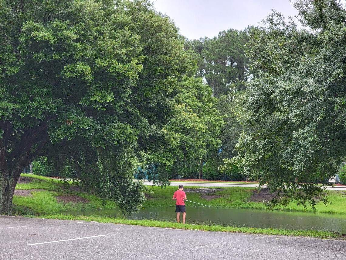A boy fishes in elevated water outside of Pelicans Ballpark during Tropical Storm Debby.