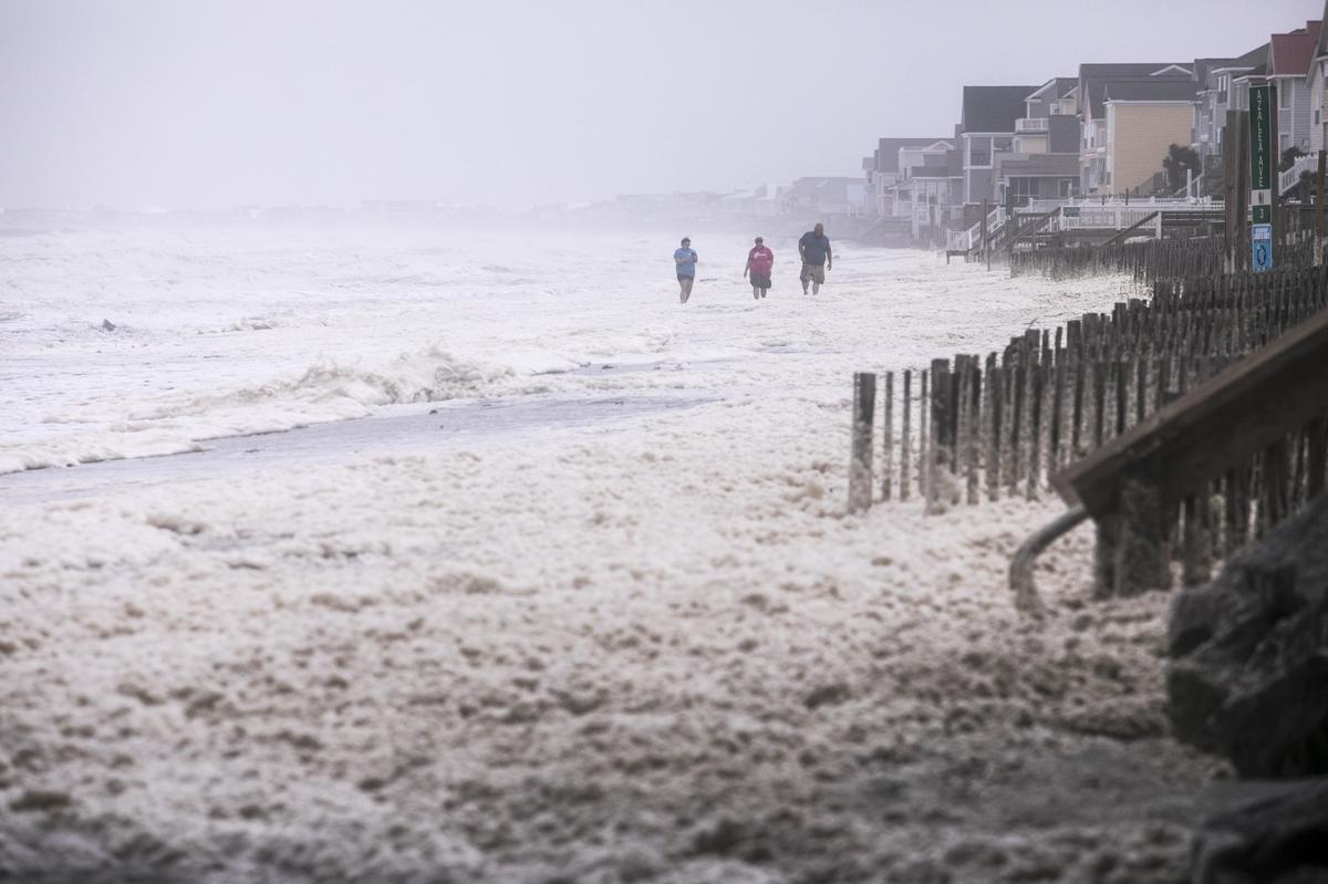 Beach combers wade through blowing foam in Garden City as the remnants of Hurricane Michael passed through the Grand Strand bringing high winds, and coastal flooding on Thursday. Oct. 11, 2018