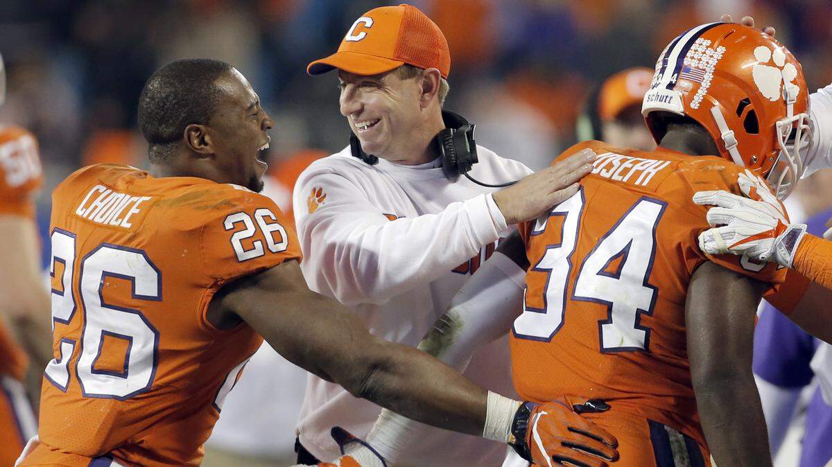 FILE - In this Dec. 2, 2017, file photo, Clemson head coach Dabo Swinney, center, congratulates his players during the second half of the Atlantic Coast Conference championship NCAA college football game against Miami, in Charlotte, N.C. The Tigers are pursuing their fourth straight Atlantic Coast Conference championship and have lost two league games in three seasons. (AP Photo/Bob Leverone, File)