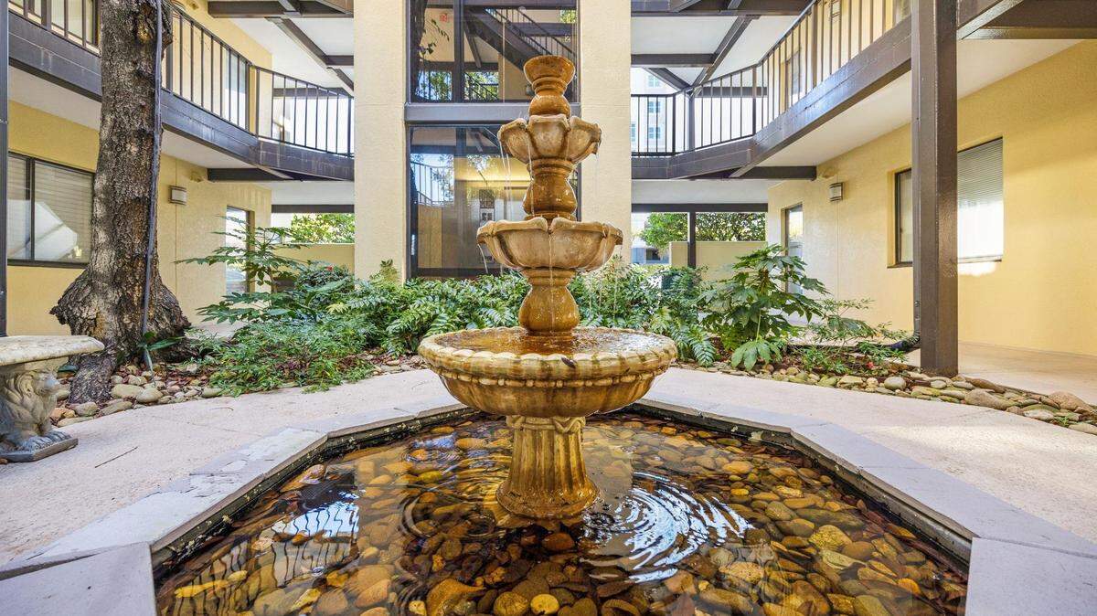 The indoor patio of The Atrium. There is a fountain and the glass elevator in the back.