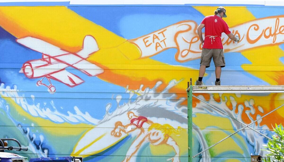 Myrtle Beach native, now living in San Clemente, CA, Drew Brophy paints a mural on the wall of Lulu’s Cafe in Myrtle Beach, Friday afternoon. The completed work, the largest he has done, will be 61x16 feet and require over 400 cans of graffiti paint to complete. 08/31/12__Photo by Charles Slate