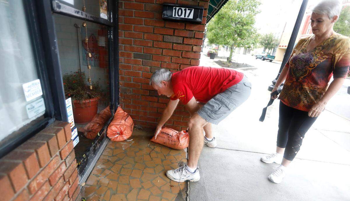 Mike and Dottie Klein place sandbags in front of their door after checking on their business, Rivertown Yoga, in downtown Conway, S.C. Saturday, Sept. 15, 2018. 