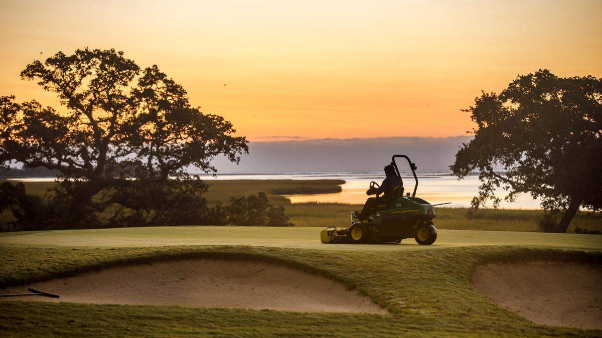 James Kurtz mows the 13th green at Tidewater Golf Club just before sunrise over the Hog Inlet salt marsh. Oct. 11, 2024.
