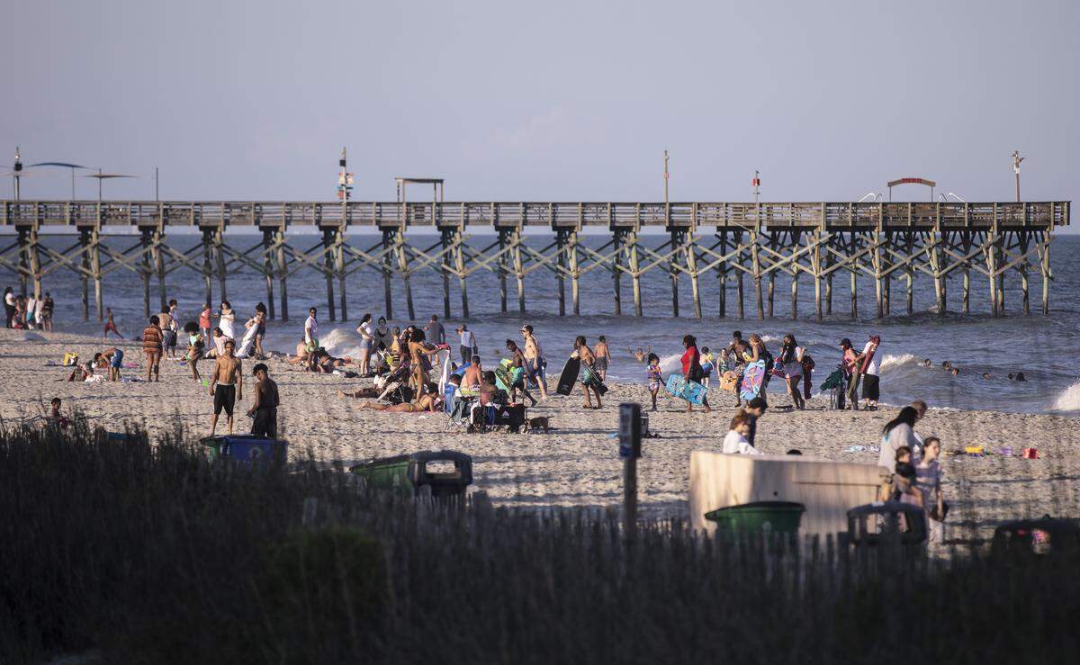 Sunbathers catch the last rays of light on Myrtle Beach on Saturday. Though barricades were in place, this Saturday of Memorial Day weekend looked much different from years past. With Bike Fest postponed, family groups, some wearing masks walked Ocean Boulevard. May 23, 2020
