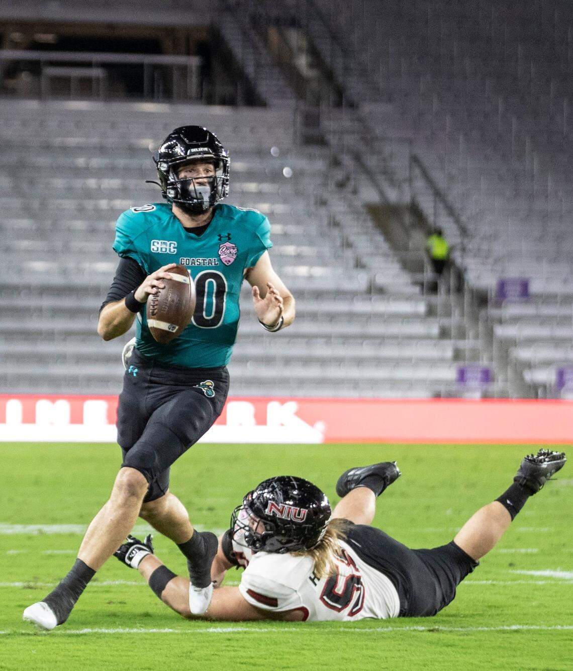 Coastal Carolina quarterback Grayson McCall (10) steps out of the grasp of a Northern Illinois defender during the Cure Bowl NCAA college football game in Orlando, Fla., Friday, Dec. 17, 2021. (Willie J. Allen Jr./Orlando Sentinel via AP)