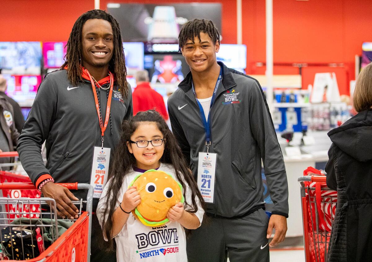 Waccamaw receiver Tyree Funnye (left) stands with Boiling Springs defensive back Marquise Graves (right) and Myrtle Beach Elementary student Neylin Lopez at Target in Myrtle Beach Thursday afternoon as football players from the North and South squads playing in the 2019 Touchstone Energy Bowl take Myrtle Beach Elementary students shopping. The players were given a $150 Target gift to help the students shop for items on their wish lists.