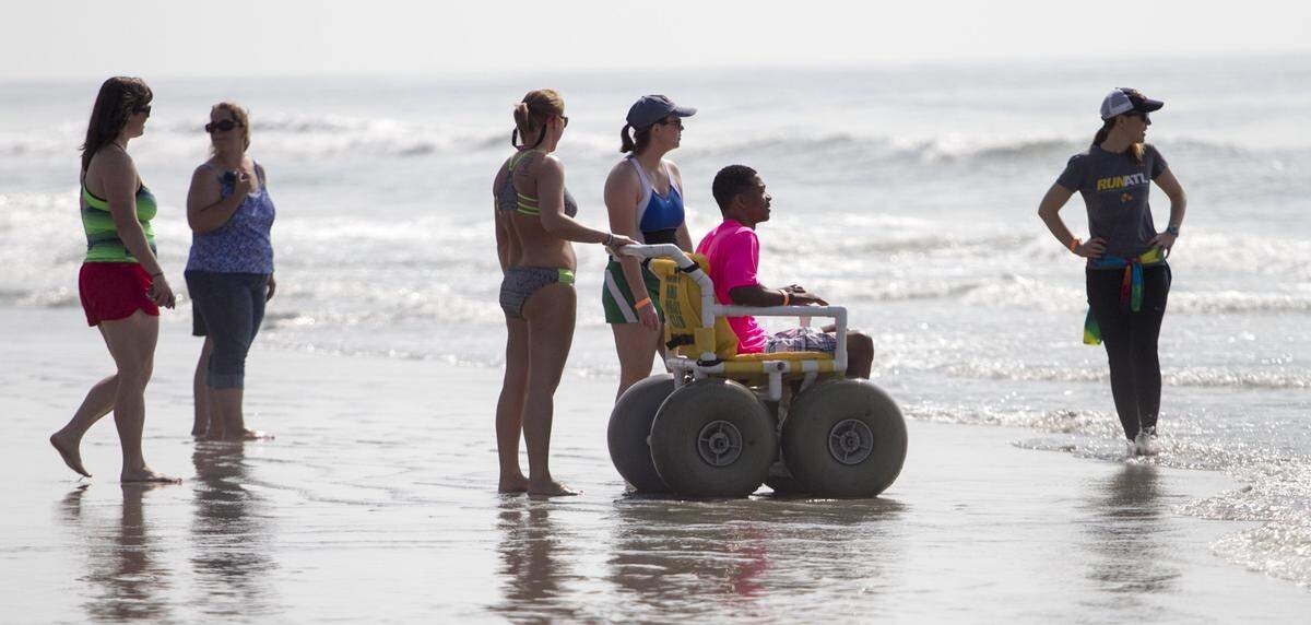 A surfer waits in a beach wheel chair for a chance to hit the waves at the “Wheel to Surf” Adaptive Surfing Clinic held in North Myrtle Beach on Saturday. Forty participants with mental and physical disabilities took to the water with help from over 100 volunteers. “Today is a life changing experience for most of us,” said Brock Johnson, founder of “Wheel to Surf.” The clinic was hosted with support from Coastal Adaptive Sports, Ocean-Cure, and the Adaptive Sports Project.