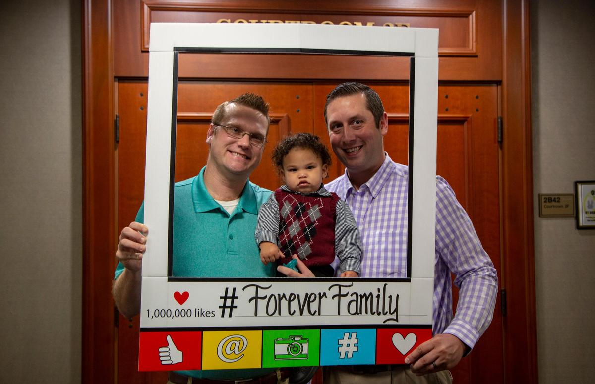 Christopher Rexford (L) and Stephen Mathison (R) stand with their newly-adopted son Xander Monday at the Horry County Courthouse in Conway.