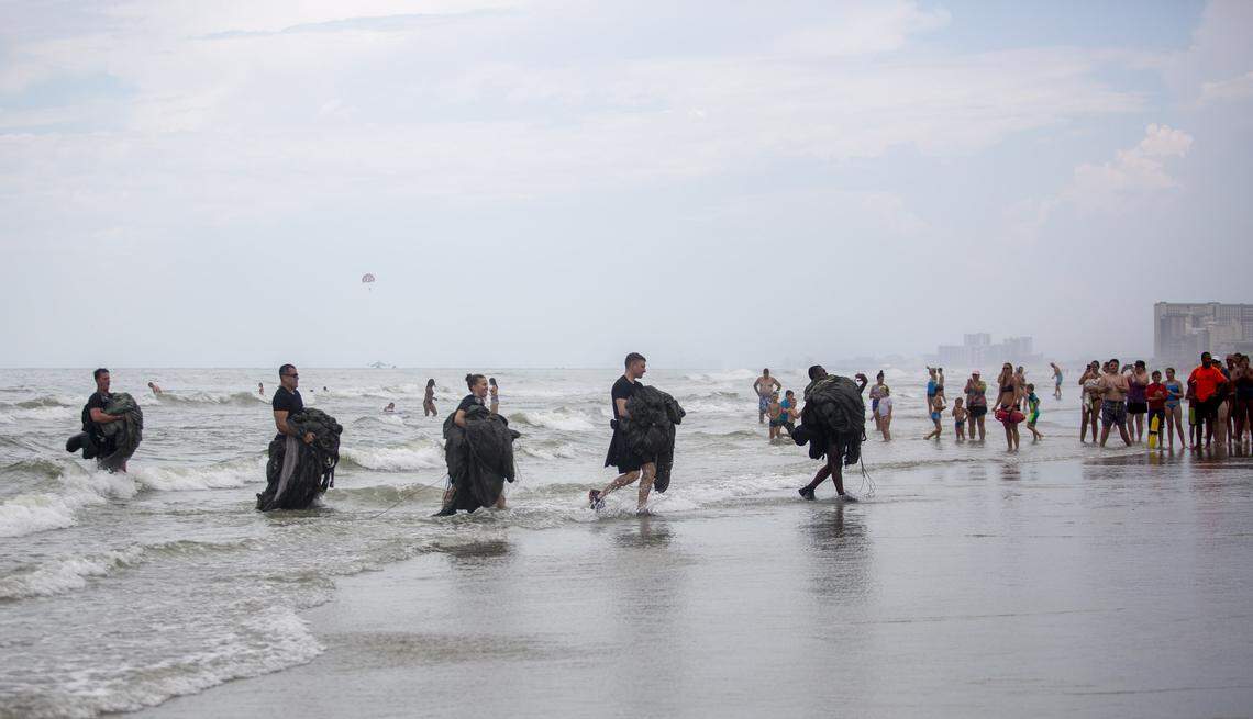 Soldiers from the United States Army Special Operations walk onto the beach after parachuting down into the ocean from Blackhawk helicopters near 27th Avenue South in North Myrtle Beach Thursday afternoon. Tourists and locals gathered on the beach to watch.
