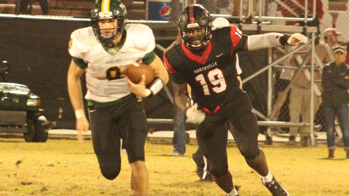 Myrtle Beach quarterback Luke Doty (9) escapes the pressure of Hartsville’s Demonte Capehart (19) during Thursday’s regular season finale, won by Hartsville 70-34.