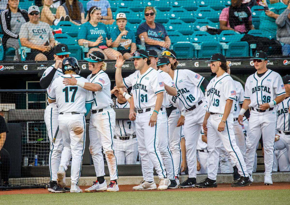 Coastal Carolina players congratulate Matt McDermott after he scores in the third inning against Kent State during the Baseball at the Beach Tournament at Spring Brooks Stadium in Conway on Friday afternoon. February 18, 2022.