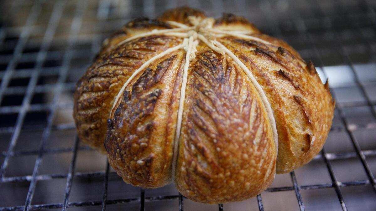 Audrey Brletich and James Levy pull sourdough bread from the oven at Leve’ bakery. Leve’ prepares sourdough bread for their retail shop and farmers market. They prepare 50 to 60 loaves a day. Oct. 23, 2024.