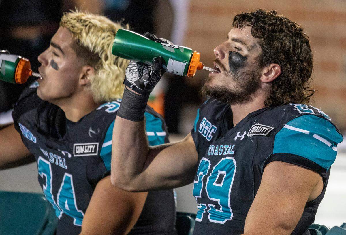 Coastal Carolina’s Teddy Gallagher and Silas Kelly, sporting their mullets, take a break during a game against BYU on Dec. 5, 2020.