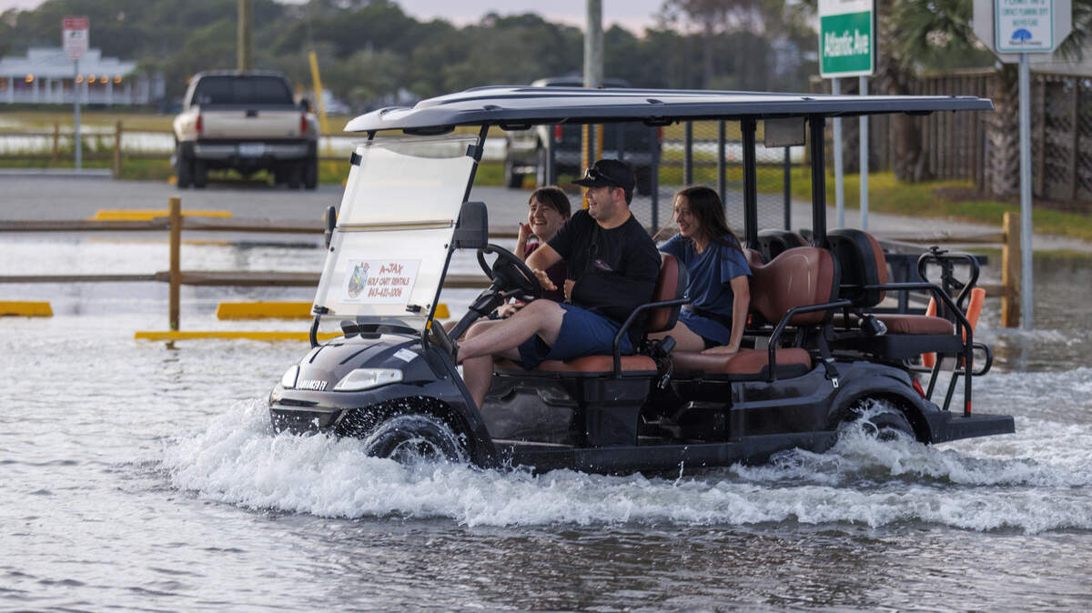 A golf cart renter drives through salty flood waters caused by king tides in Garden City, SC .on  Friday, Oct.4, 2025.
