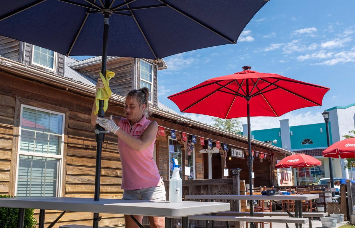 Dietka Stogner, General Manager for Hamburger Joe’s in Surfside Beach, S.C. wipes down new umbrellas before the start of outdoor dining. Rules for outdoor dining in South Carolina amid the coronavirus were relaxed on Monday. May 4, 2020