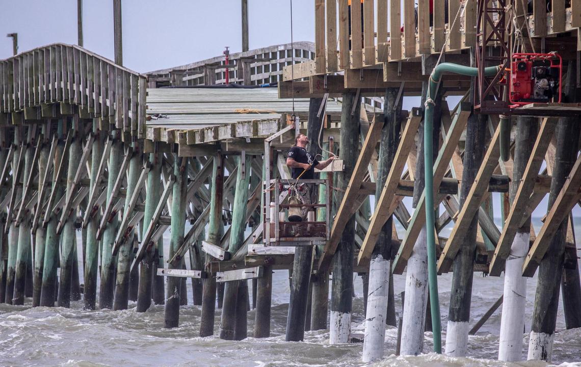 A worker hangs from a crane to work on repairs of the Cherry Grove Pier in North Myrtle Beach, S.C. The pier is undergoing repairs after the landmark was damaged from Hurricane Ian in September 2022. June 23, 2023.
