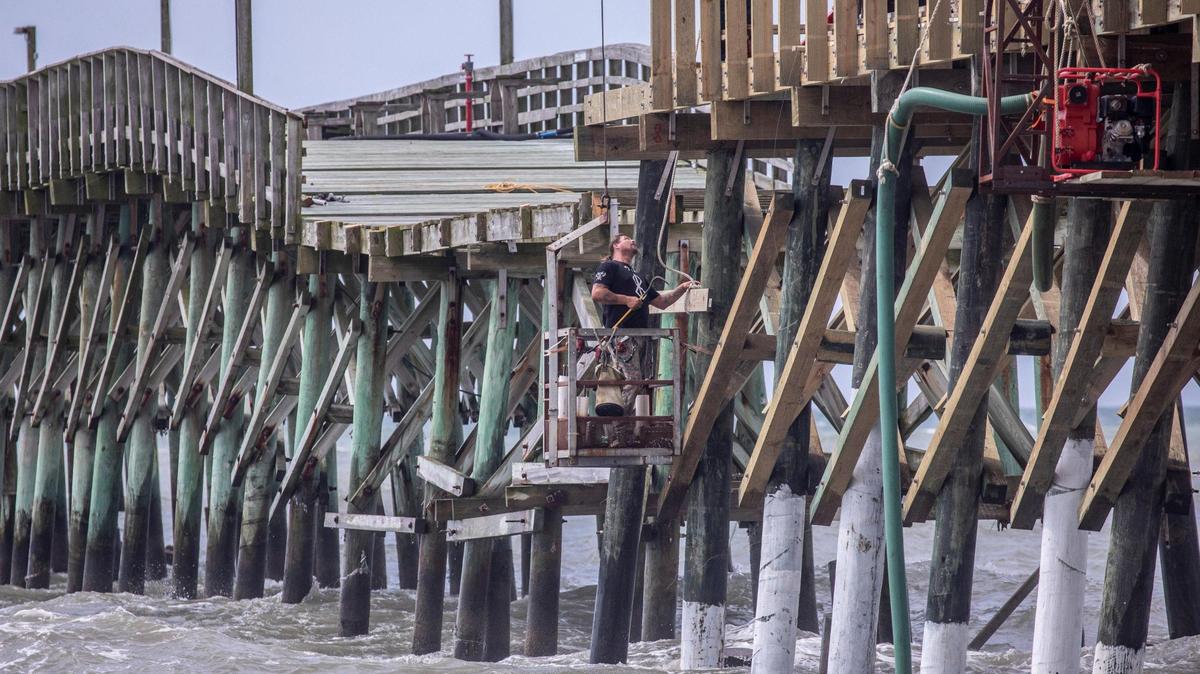 A worker hangs from a crane to work on repairs of the Cherry Grove Pier in North Myrtle Beach, S.C. The pier is undergoing repairs after the landmark was damaged from Hurricane Ian in September 2022. June 23, 2023.