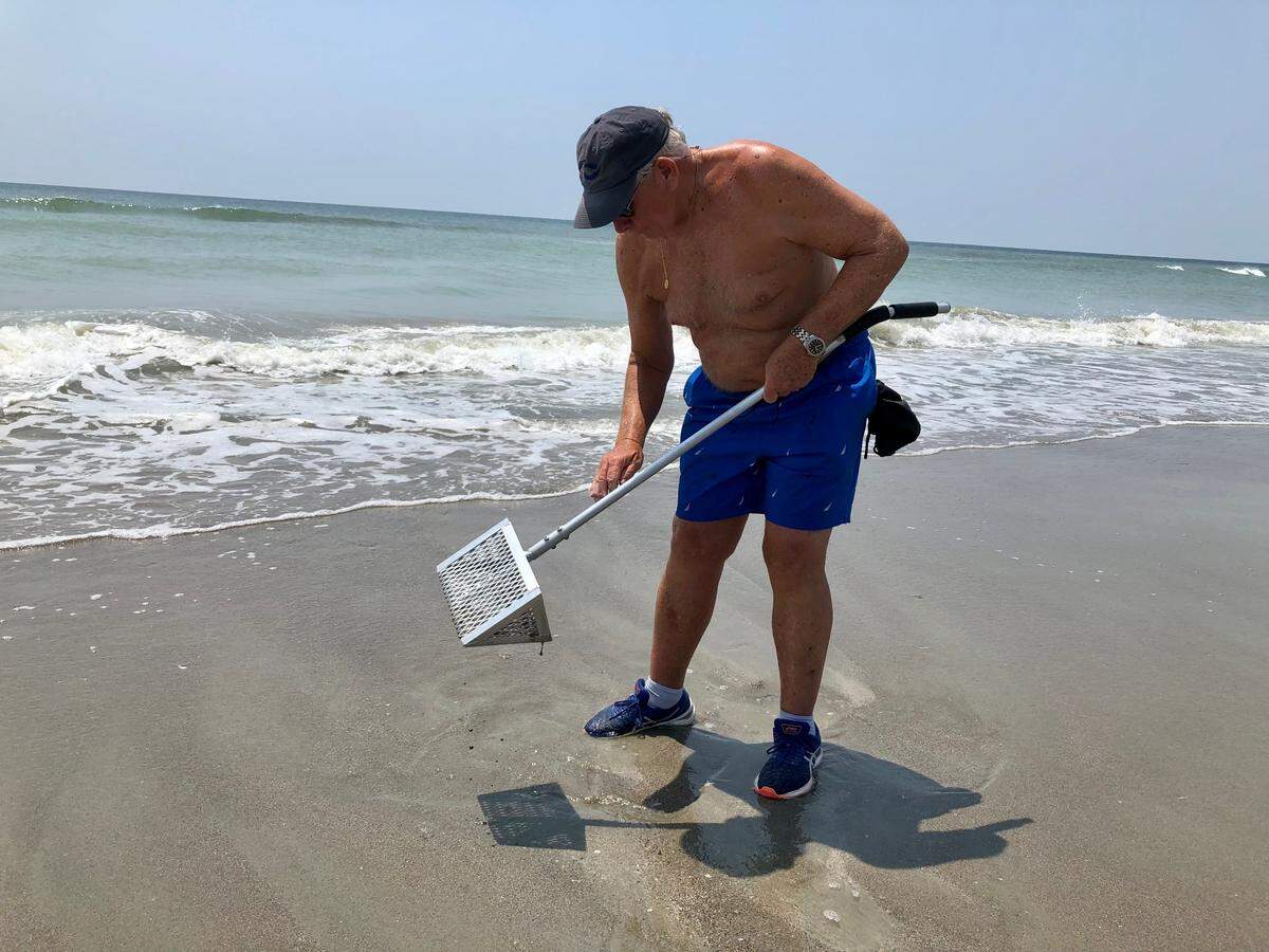Chuck Farthing of Harrisonburg, Virginia looks for shells at Holden Beach, N.C. Seashell hunters flock to the island to look for coveted sea biscuits in the sand. August 2, 2023.