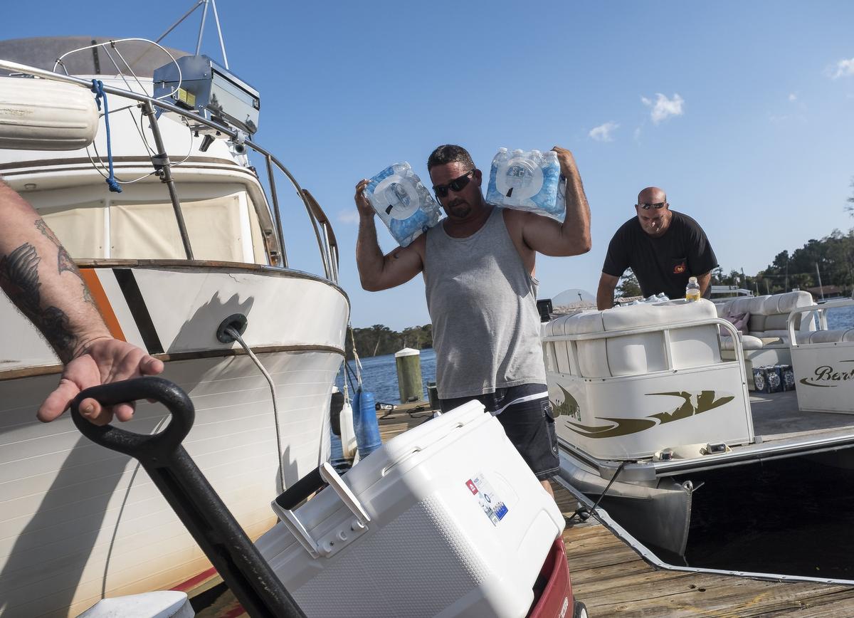 Phil Gerber shoulders bottles of water to a friend who is living on a boat at Bucksport Marina who has been cut off from supplies by rising flood waters. The Waccamaw River at Conway crested Wednesday at well over 21 feet flooding many downtown homes. Wednesday, Sept. 26, 2018.