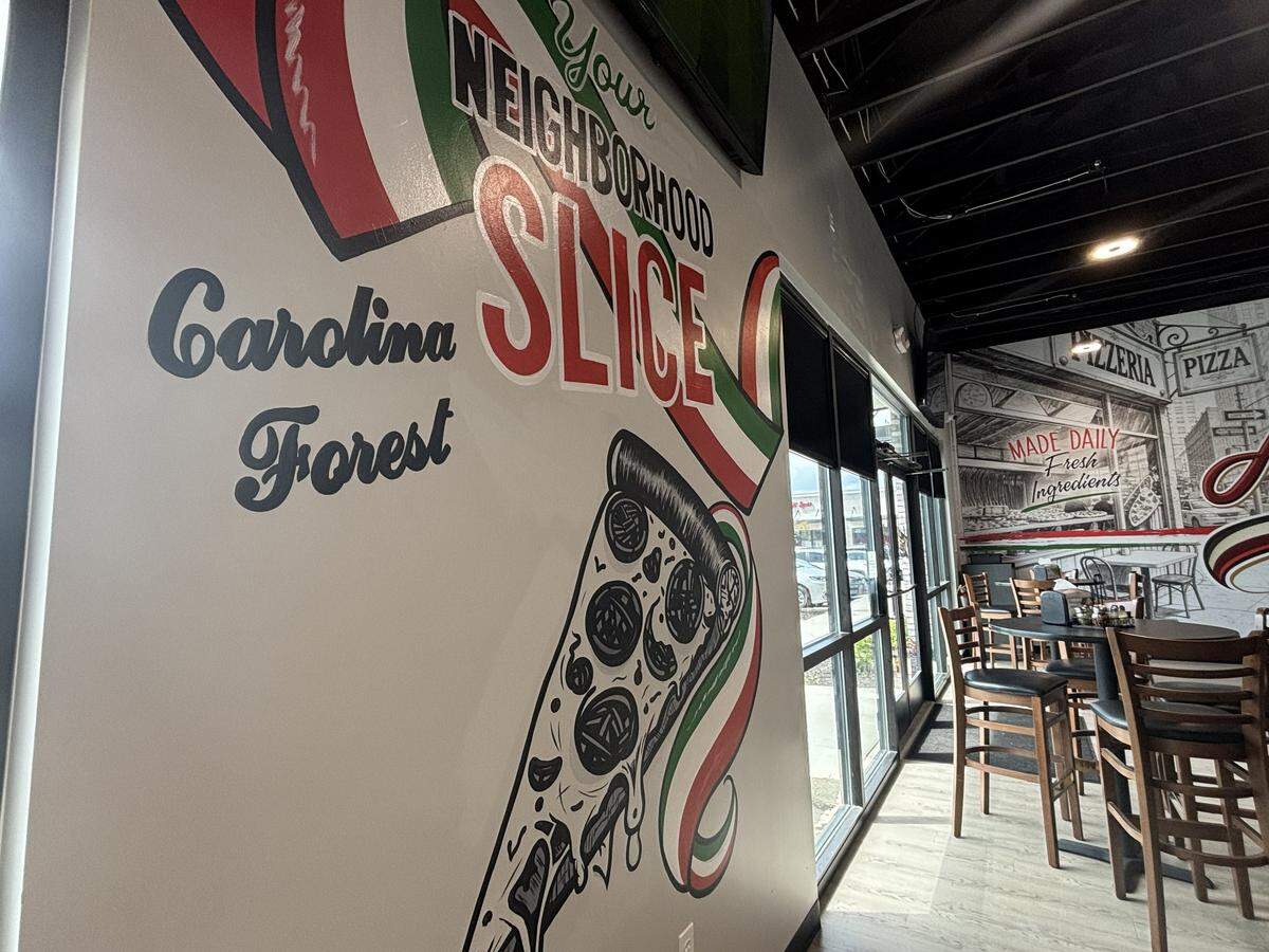 A painting of Amici Pizza’s slogan “Your Neighborhood Slice” sits on one of the walls in the restaurant on May 13, 2026. The painting was done by a local artist.
