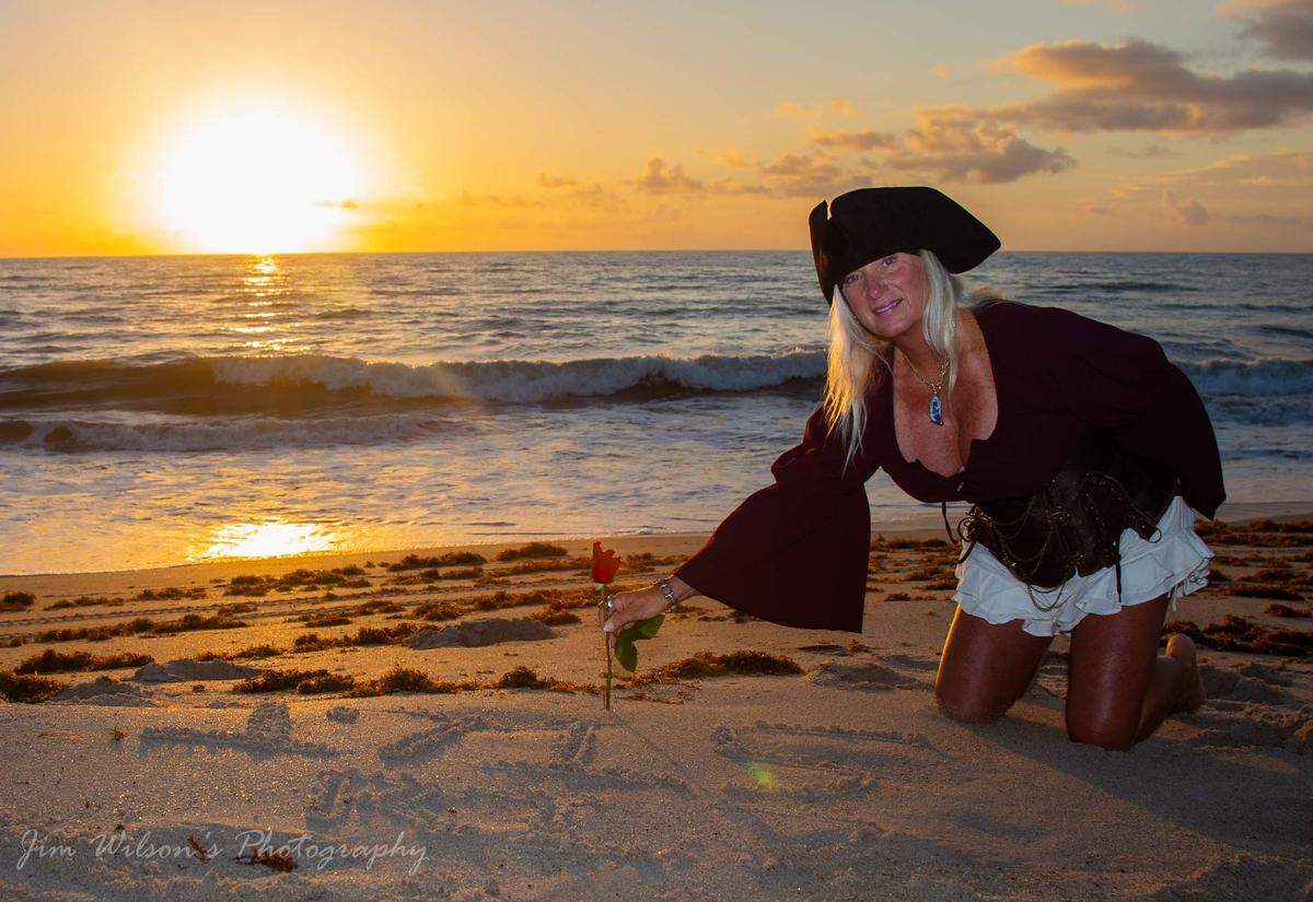 Candi Lynn Nichols, who goes by “Cutlass Candi” and identifies as a pirate, plants a rose in the sand on a Florida beach in honor of of the sailors who died when the 1715 Treasure Fleet sank and gave the Treasure Coast its name.&nbsp;