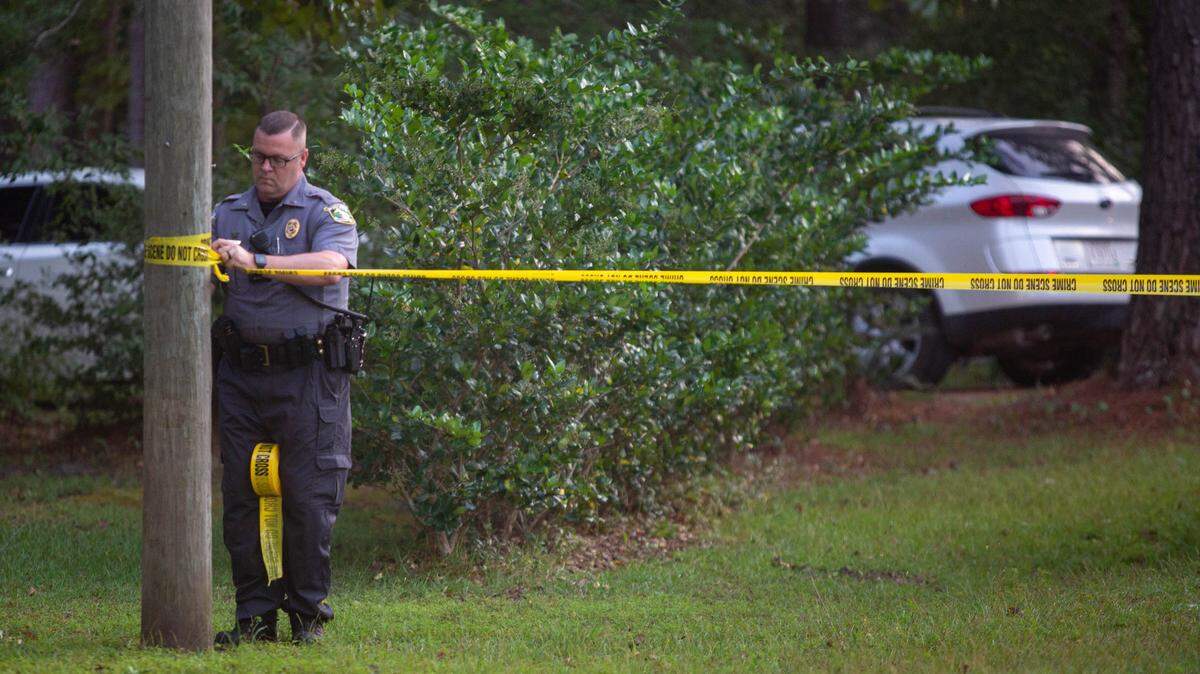 An Horry County police officer tapes off a section of road on Lilac Rd. Friday in Myrtle Beach after reports of a drowning.