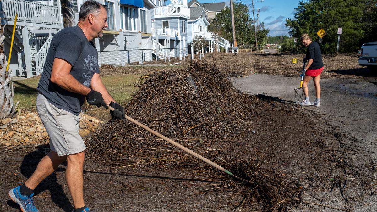 Chris and Delisa Harrison work to clean up flotsam that drifted over their yards and street as Hurricane Ian’s storm surge flooded their Cherry Grove community in North Myrtle Beach on Saturday, October 1, 2022.