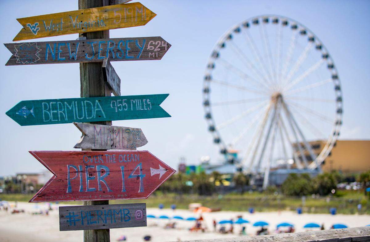 Signs point to various locations along Pier 14 with the Myrtle Beach SkyWheel looming in the background Sunday afternoon in Myrtle Beach as Tropical Storm Isaias approaches the coast, and the coronavirus pandemic continues to spread. At least 91,257 people have tested positive for the coronavirus in South Carolina and 1,709 have died, according to state health officials.