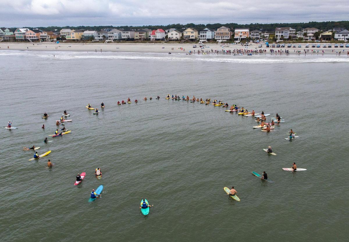 A paddle out ceremony was held for the late Cpl. Michael Ambrosino, a beach patrol officer who died of COVID-19 related illness earlier this month. During the ceremony members of HCPD Beach Patrol, local ocean rescue teams, lifeguards, divers, and other friends and family paddled out from the shore arranging themselves in a a human circle, to share a few words about Cpl. Ambrosino and lay flower leis in the surface of the ocean. September 26, 2020.