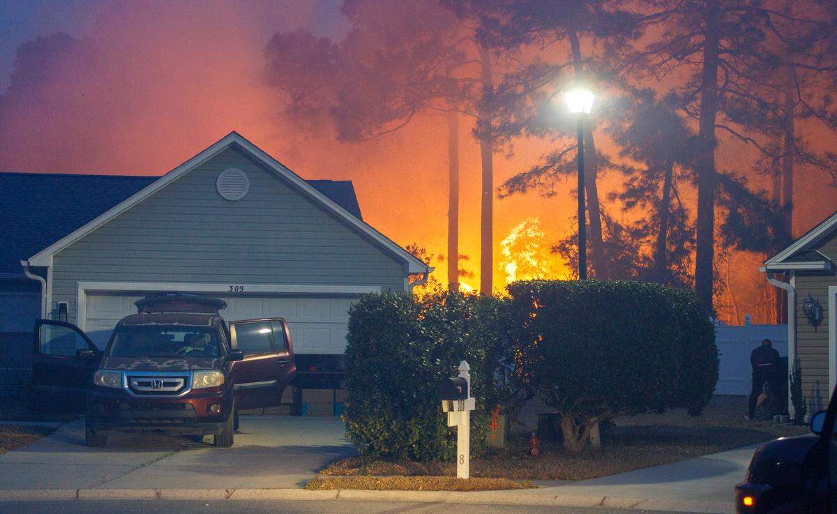 A home on Centennial Court in Walkers Woods is threatened as the woods catch fire behind the home. Firefighters quickly extinguished the blaze. Evacuations continued over night for communities in the Carolina Forest area threatened by a forest fire. Firefighters and residents worked to protect their homes from the flames. Sunday, March 2, 2025.