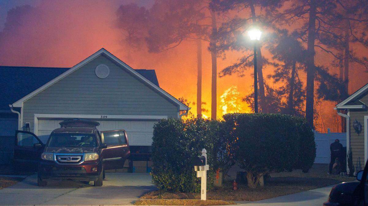 A home on Centennial Court in Walkers Woods is threatened as the woods catch fire behind the home. Firefighters quickly extinguished the blaze. Evacuations continued over night for communities in the Carolina Forest area threatened by a forest fire. Firefighters and residents worked to protect their homes from the flames. Sunday, March 2, 2025.