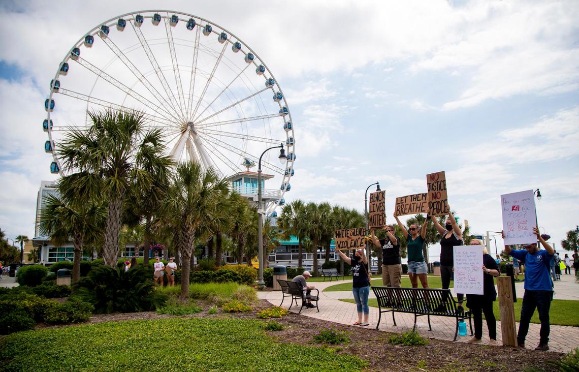 Protesters hold signs in honor of George Floyd at Plyler Park in Myrtle Beach Sunday morning to protest the death of Floyd, who was killed while in police custody in Minneapolis, Minn. last week.