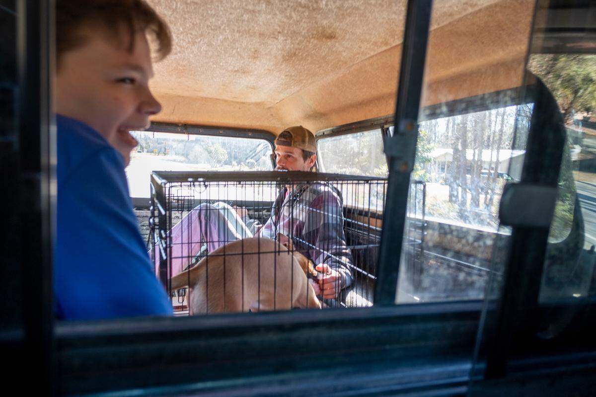 Joseph Long and his son Maddox sit in the back of his truck after making their way through the flooded neighborhood. They will spend the week with a friend until water levels go down.