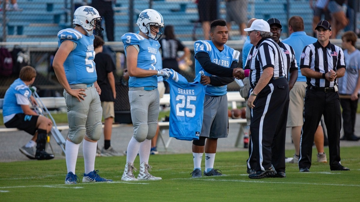 St. James players bring the jersey of injured teammate Pierson Thames to the field prior to their game Monday against West Florence.