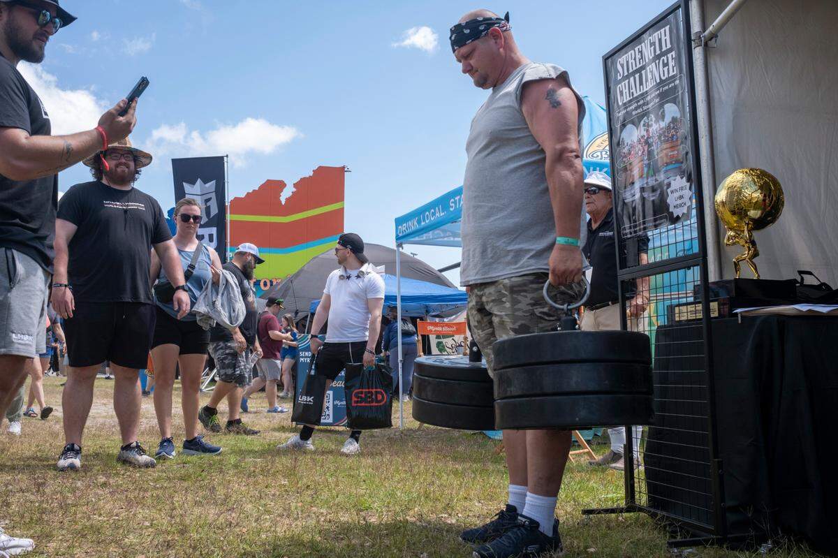 A fan attempts a version of one of the lifts at the 2024 World’s Strongest Man competition. Merchandise vendors, food trucks, and a big screen showing the competition in real time are set up on the site and free to the public. Several offer spectators an opportunity to try versions of the lifts the athletes perform. Wednesday, May 1, 2024.