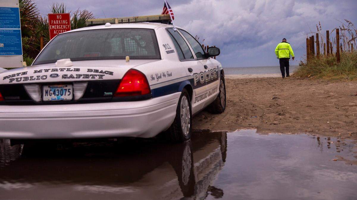 A North Myrtle Beach police officer walks toward the beach in Cherry Grove as a curfew begins at 7 p.m. Thursday.
