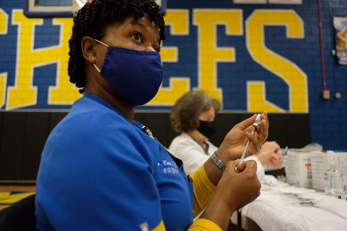Dr. Elena Gore, an OBGYN and North Myrtle Beach High School alumni, fills syringes with the Pfizer COVID-19 vaccine during Saturday’s mass vaccination event at the high school.
