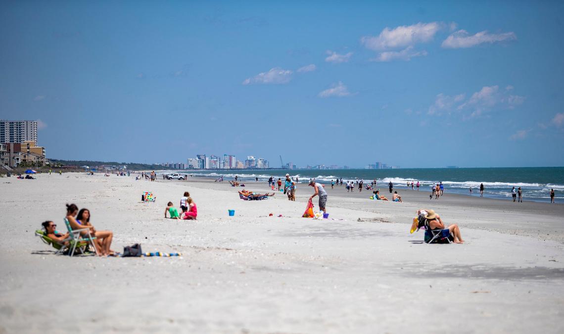 People lay out and walk along the beach near the Surfside Pier Tuesday afternoon in Surfside Beach.