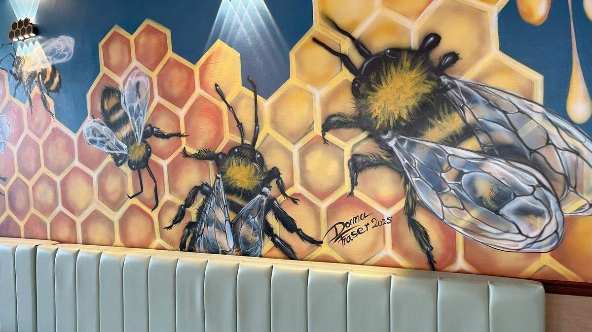 A custom mural by Dorina Fraser lining the booths in the back of the Salt and Honey brunch restaurant. May 21, 2025.