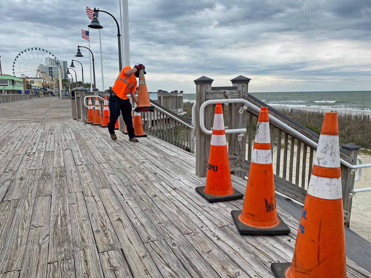 A city worker places cones across the Myrtle Beach boardwalk on Tuesday. Myrtle Beach Public Works crews were closing down public beach access points following S.C. Governor Henry’s McMaster’s order to close access to beaches and public waterways amid the coronavirus threat. March 31, 2020.